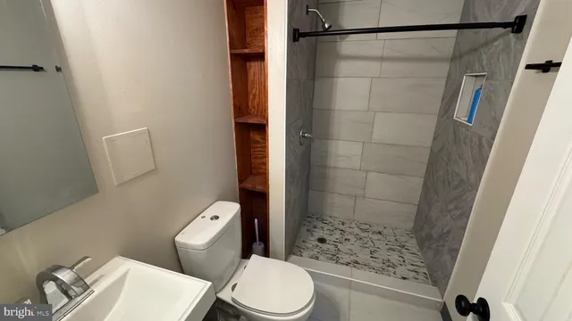 a white toilet sitting next to a bathroom sink and a shower