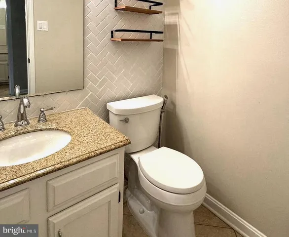 a bathroom with a granite countertop toilet sink and mirror