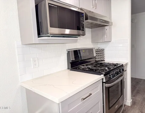 a kitchen with stainless steel appliances a stove microwave and sink