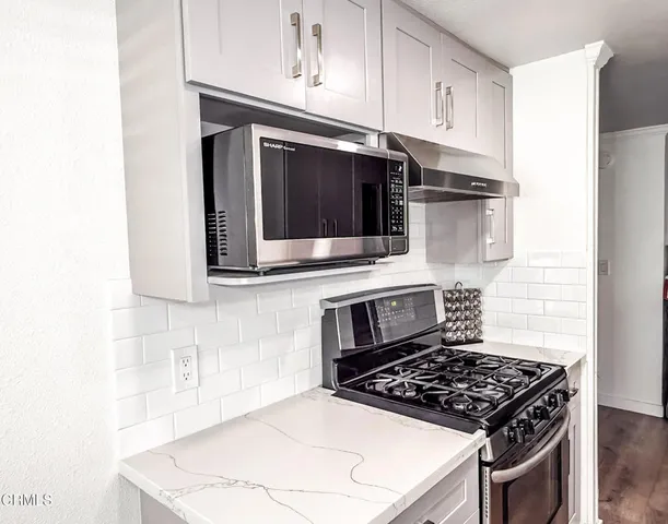 a kitchen with stainless steel appliances a stove a microwave a sink and cabinets