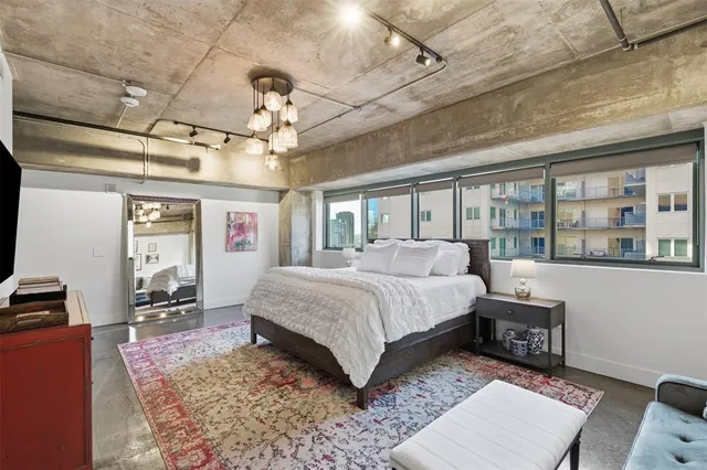 a spacious bedroom with a bed a bookshelf and a chandelier
