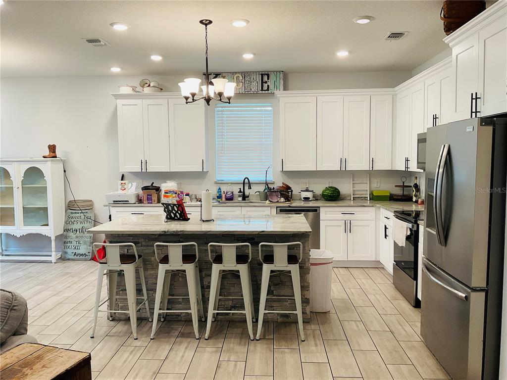 515 5th Street South Dundee, FL 33838 - Photo 60 of 74 a kitchen with stainless steel appliances granite countertop a table chairs sink refrigerator and microwave
