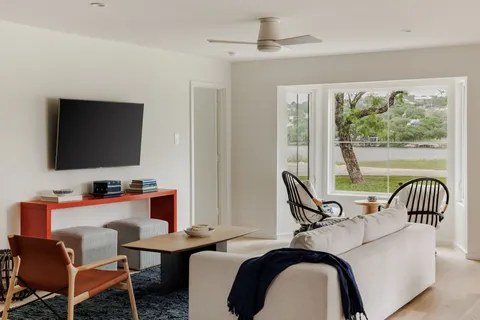 a living room with furniture floor to ceiling window and a flat screen tv