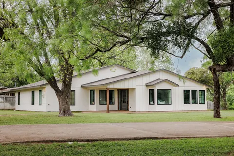 a white house that has a tree in front of the house