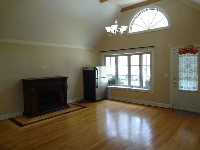 an empty room with wooden floor fireplace and windows