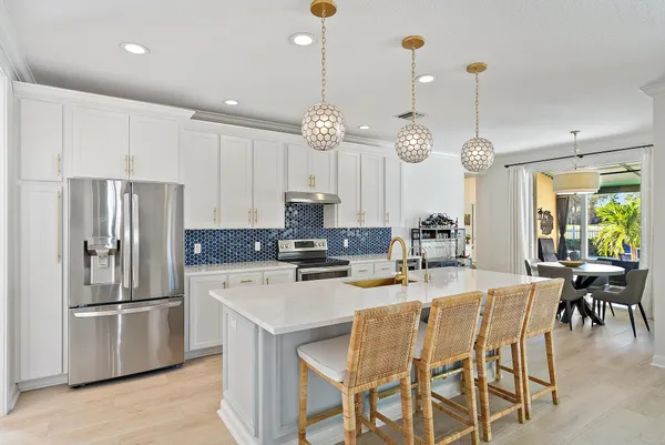 a kitchen with stainless steel appliances kitchen island granite countertop a dining table chairs and white cabinets
