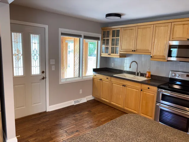 a kitchen with granite countertop wooden cabinets stainless steel appliances a sink and a window