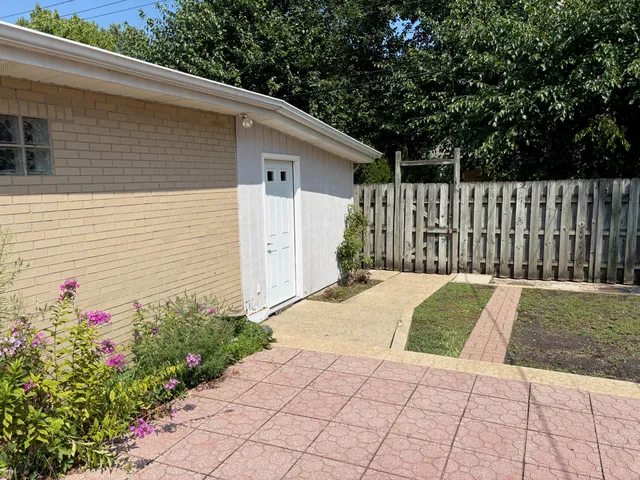a view of a white house with a small yard and flower plants