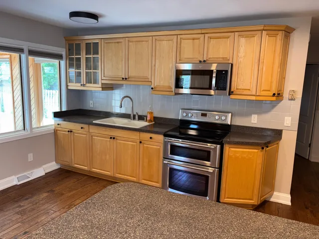 a kitchen with stainless steel appliances granite countertop a stove a sink and a microwave