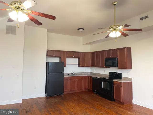 a kitchen with stainless steel appliances granite countertop a refrigerator a sink dishwasher a stove and a dining table with wooden floor