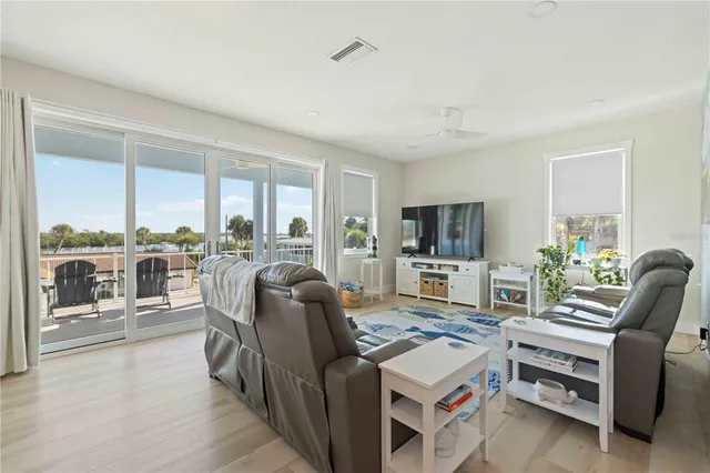 a living room with furniture a flat screen tv and a floor to ceiling window