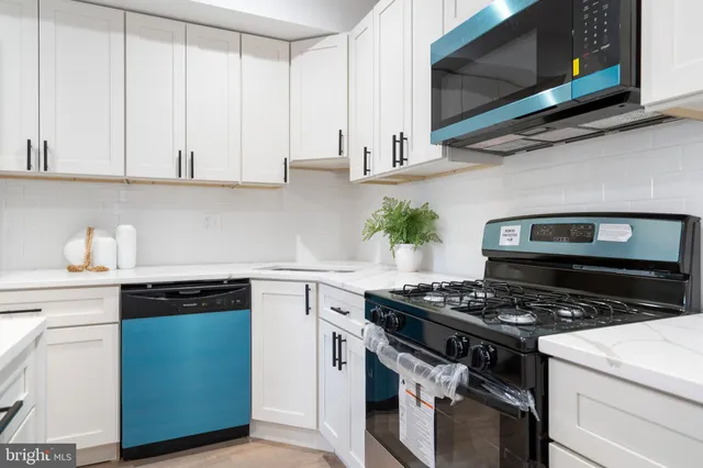 a kitchen with stainless steel appliances granite countertop white cabinets a stove a sink and dishwasher