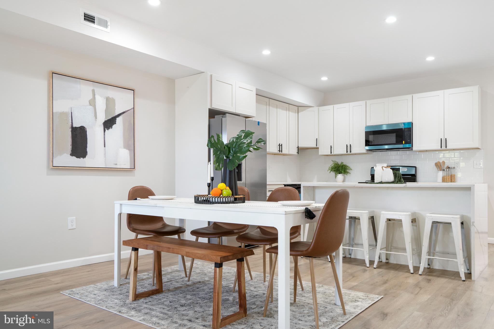 4011 Ridgewood Avenue Baltimore, MD 21215 - Photo 14 of 35 a kitchen with a table chairs refrigerator and microwave