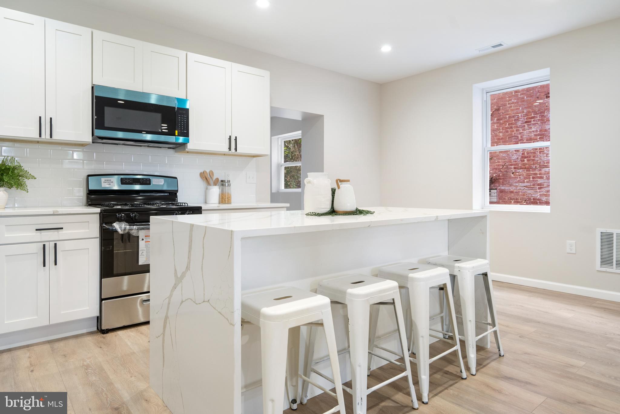 4011 Ridgewood Avenue Baltimore, MD 21215 - Photo 9 of 35 a kitchen with stainless steel appliances a stove a sink a microwave a refrigerator and white cabinets