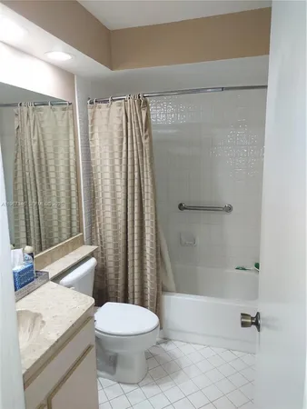 a bathroom with a granite countertop bathtub shower sink vanity and toilet