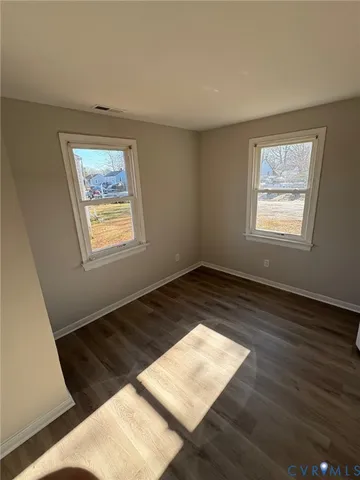 a view of an empty room and wooden floor and a window