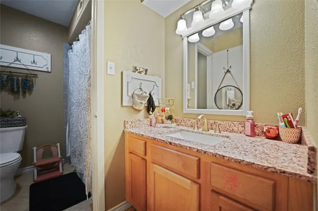 a bathroom with a granite countertop sink a toilet and a mirror