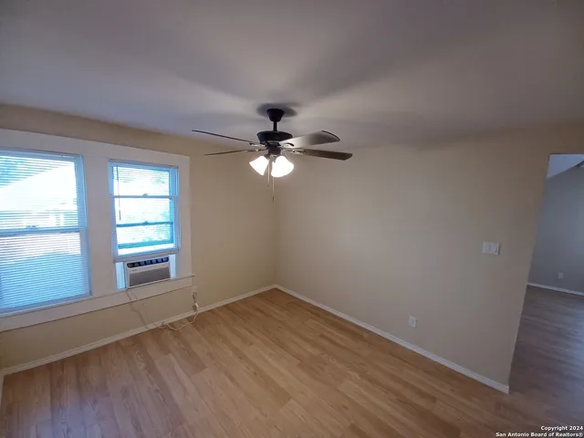 a view of empty room with wooden floor and fan