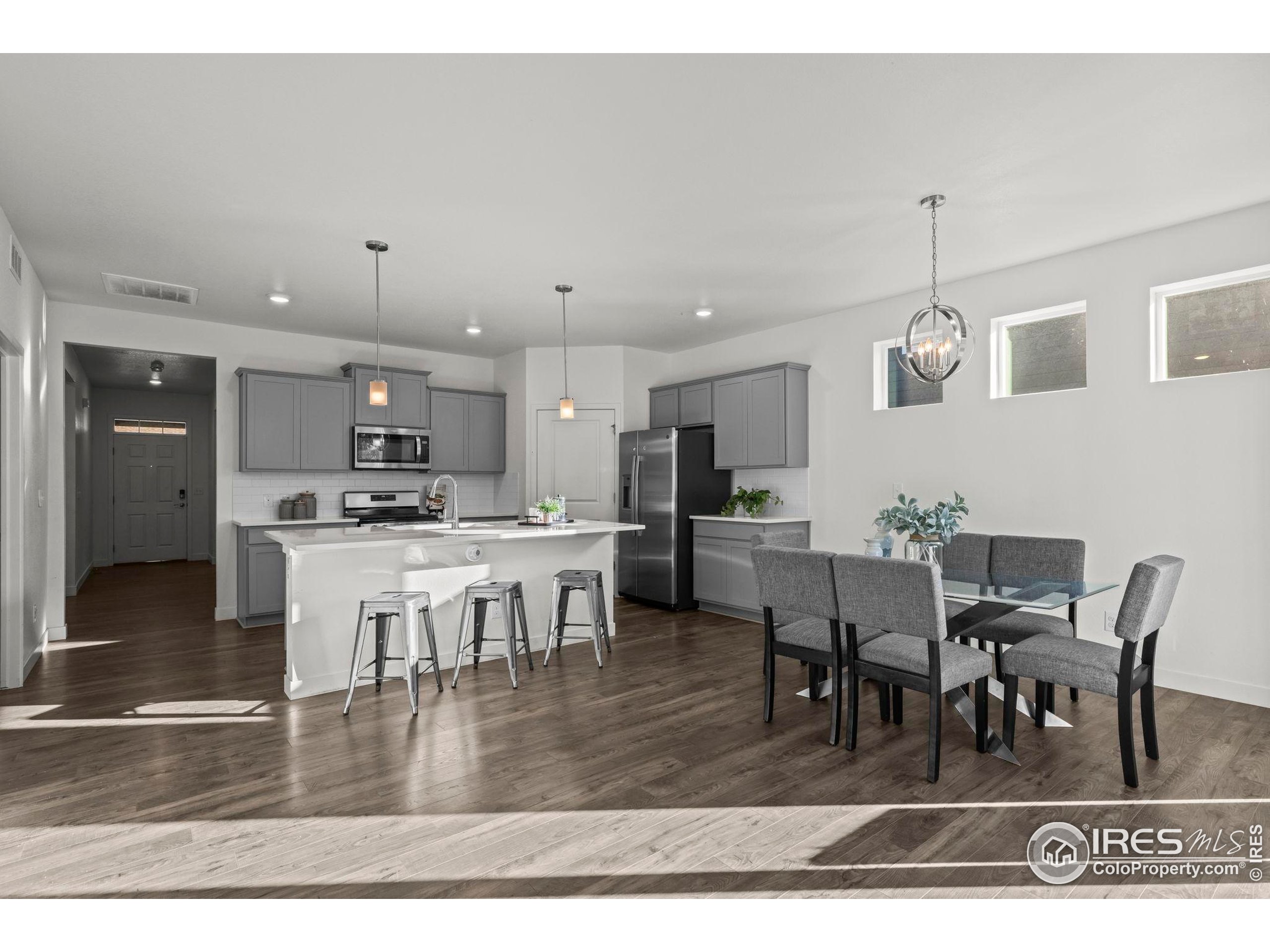 8957 Ferncrest Street Firestone, CO 80504 - Photo 13 of 50 a kitchen with stainless steel appliances kitchen island granite countertop a dining table chairs and white cabinets