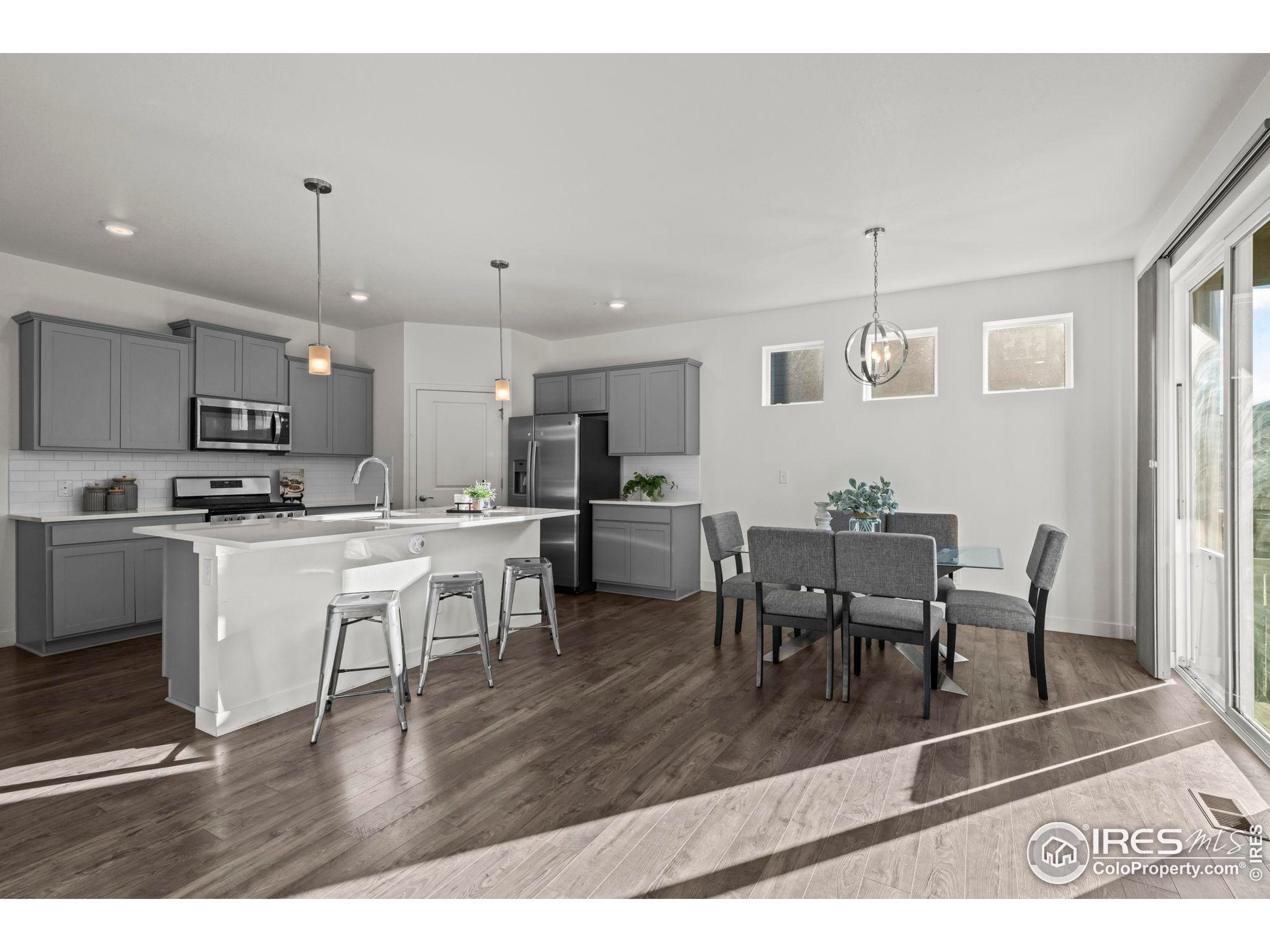 8957 Ferncrest Street Firestone, CO 80504 - Photo 14 of 50 a open kitchen view with stainless steel appliances granite countertop a dining table chairs stove refrigerator and cabinets