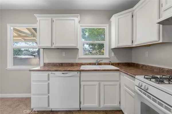 a kitchen with granite countertop white cabinets and a window