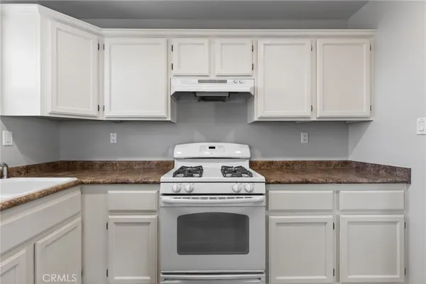 a kitchen with granite countertop white cabinets and white stove
