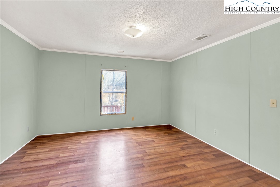 3303 Old Highway 16 Lansing, NC 28643 - Photo 20 of 30 a view of an empty room with wooden floor and a window