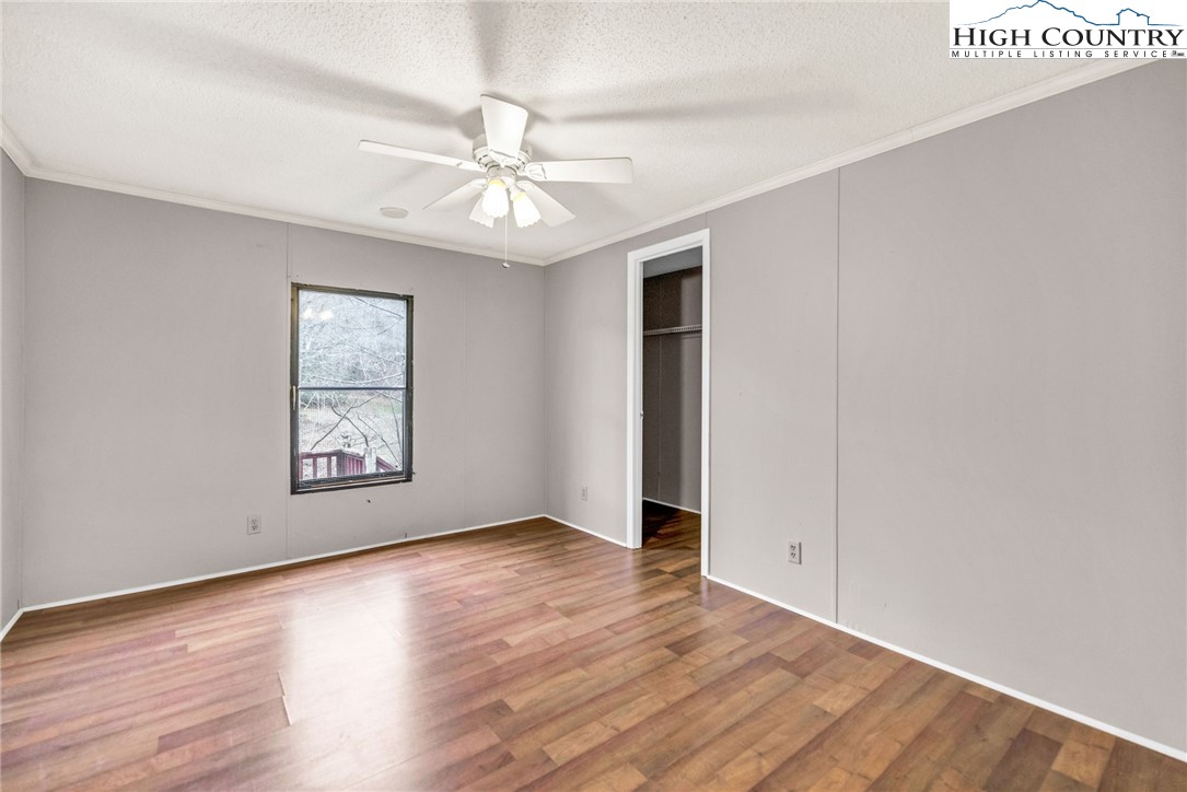 3303 Old Highway 16 Lansing, NC 28643 - Photo 25 of 30 an empty room with wooden floor chandelier fan and windows
