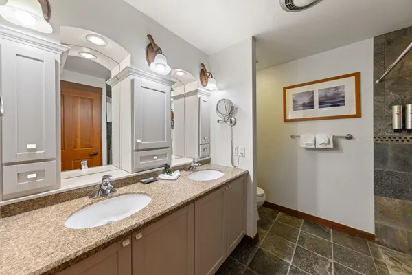 a bathroom with a granite countertop sink a mirror and a shower