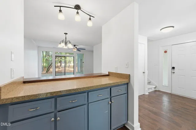 a view of a kitchen with granite countertop white cabinets and a chandelier