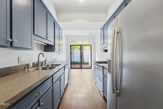 a kitchen with granite countertop a sink stove and refrigerator