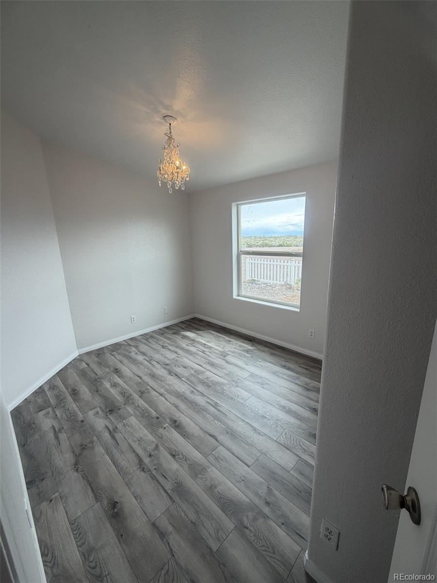 5511 Ridgetop Court Alamosa, CO 81101 - Photo 7 of 10 wooden floor in an empty room with a window