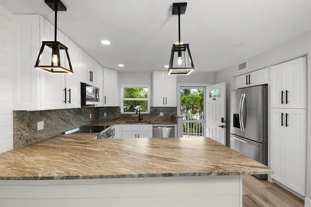 a kitchen with kitchen island a counter top a stove a refrigerator and a sink