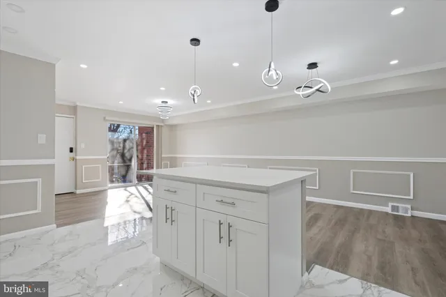 a hallway with white cabinets and chandelier