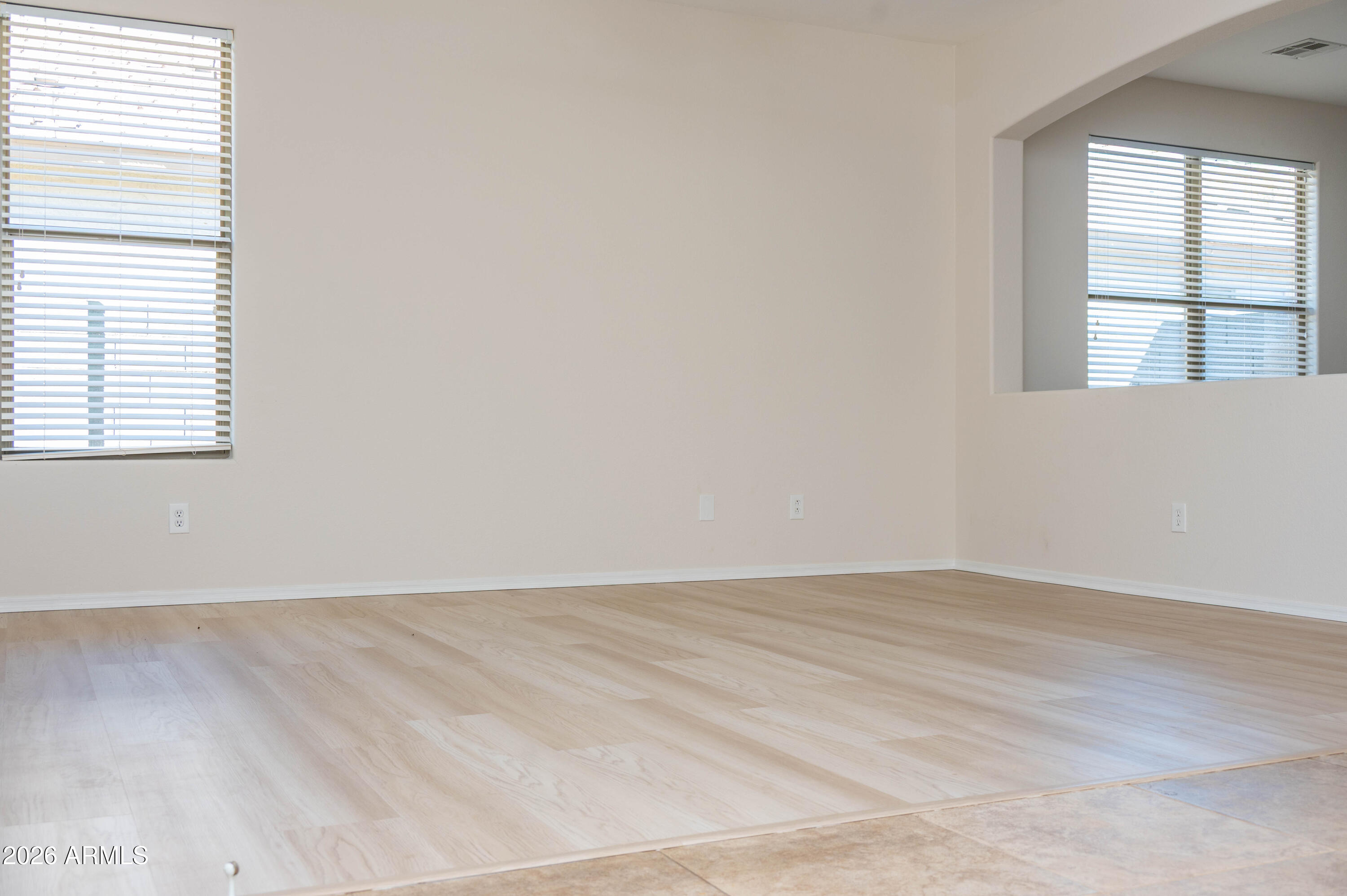 45633 West Mountain View Road Maricopa, AZ 85139 - Photo 13 of 78 an empty room with wooden floor and windows
