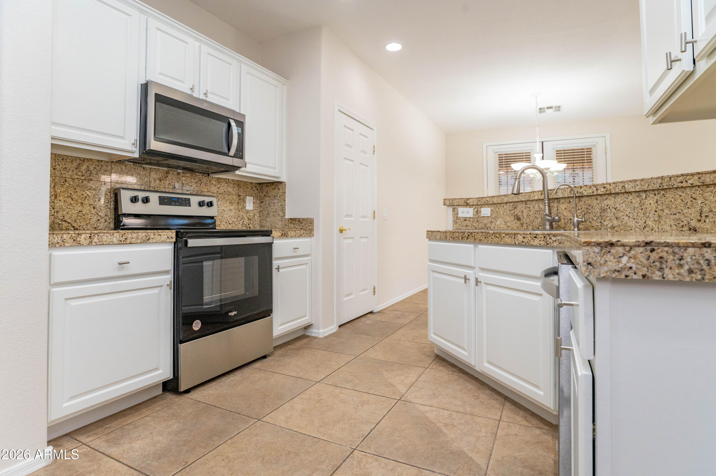 45633 West Mountain View Road Maricopa, AZ 85139 - Photo 18 of 78 a kitchen with stainless steel appliances granite countertop a stove a sink and a microwave