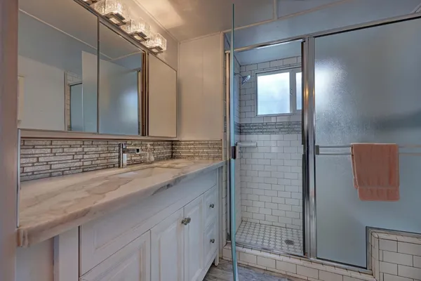 a bathroom with a granite countertop sink a mirror and shower