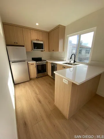 a kitchen with wooden floors a sink a stove and a refrigerator