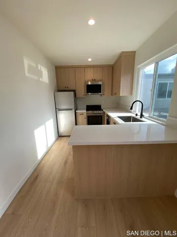 a kitchen with stainless steel appliances a sink a microwave a refrigerator and a stove top oven