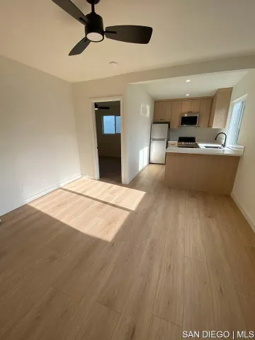 a view of kitchen and empty room with wooden floor