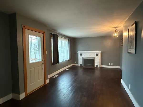 an empty room with wooden floor fireplace and windows