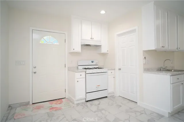 a kitchen with granite countertop white cabinets and white appliances