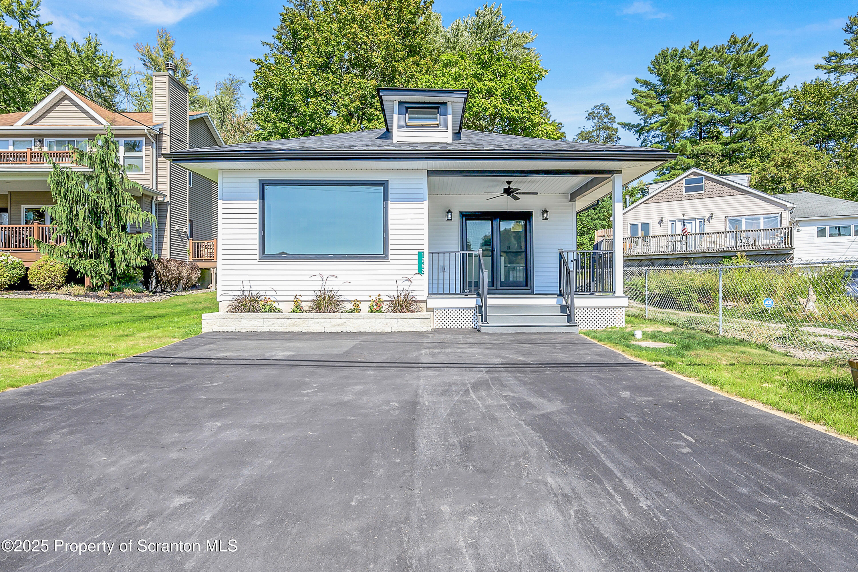 a front view of a house with a yard and potted plants
