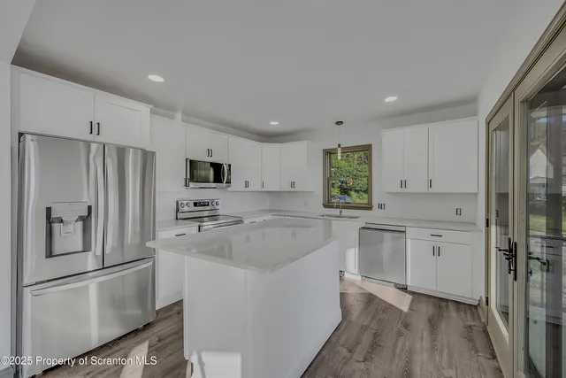 a kitchen with granite countertop a refrigerator sink and white cabinets