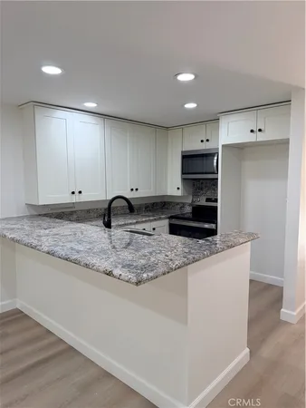 a kitchen with granite countertop white cabinets and sink