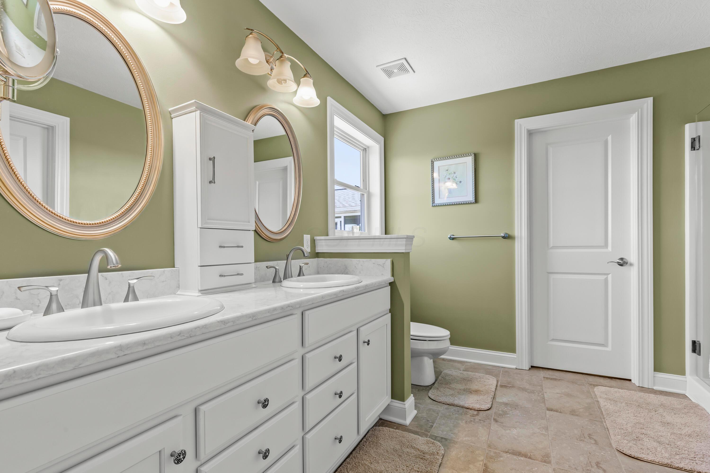 3582 Panhandle Road Delaware, OH 43015 - Photo 12 of 65 • Ceramic tile flooring • Sage painted walls • Enclosed vanity with double bowl, quartz countertop • (2) 3 bulb wall lights • Mirror remains • Cabinet does not remain • Ceiling exhaust • Shower stall with glass doors • Magnifying mirror does not remain