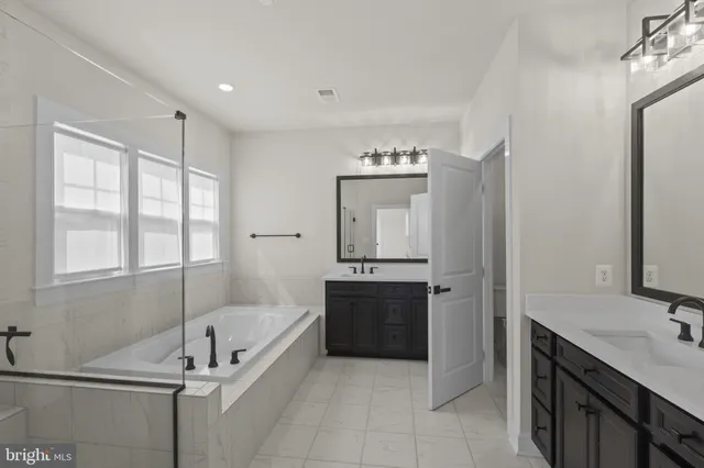 a spacious bathroom with a tub sink and mirror
