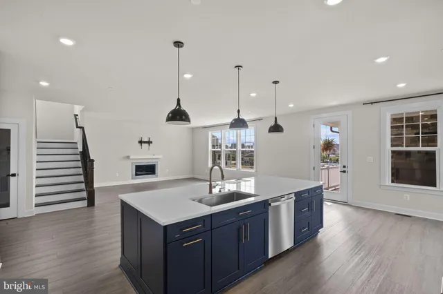 a large kitchen with kitchen island a stove a sink a center island and wooden floor