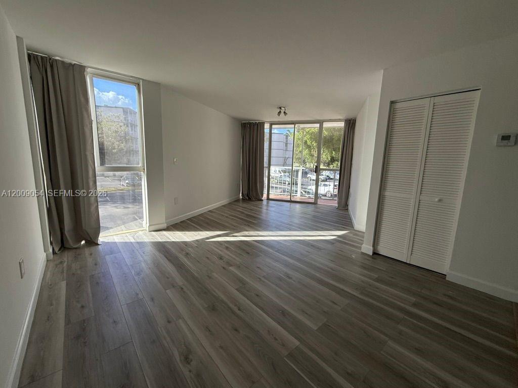 6955 Northwest 186th Street, Unit F209 Hialeah, FL 33015 - Photo 1 of 14 an empty room with wooden floor and a window