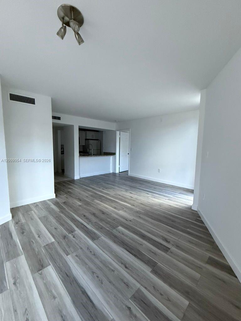 6955 Northwest 186th Street, Unit F209 Hialeah, FL 33015 - Photo 2 of 14 a view of an empty room with wooden floor and a window